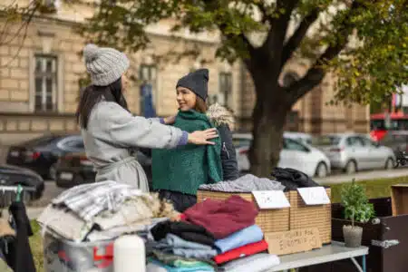 Young Woman Choosing Second Hand Clothes On Street Flea Market