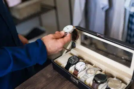 Man,is,holding,a,wristwatch,in,his,hand,,choosing,which