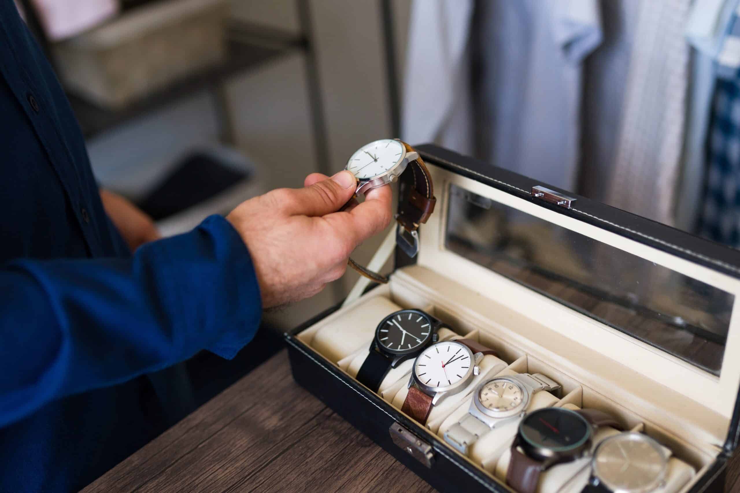 Man,is,holding,a,wristwatch,in,his,hand,,choosing,which